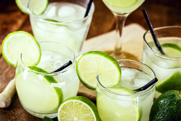 various cups and doses of caipirinha, typical Brazilian drinks, of lemon, with cachaça and sugar, on rustic wooden background, national caipirinha day, 13th September