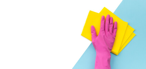 Woman's hand in pink rubber glove wipe by rag blue background