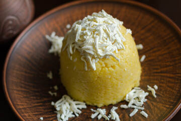 A corn porridge (mamaliga) or polenta with cheese on a dark background