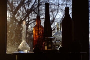 Still life by th window. Silhouette of bottles by the background light.