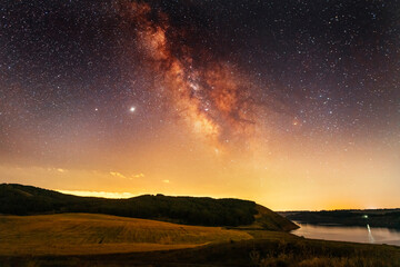 Naklejka na ściany i meble Beautiful night landscape, starry sky with bright milky way galaxy above the lake.. Astronomical background.