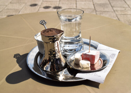 Close-up of a bosnian coffee served on a silver tray with turkish delight and a glass of cold water.