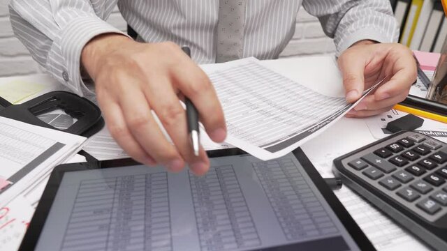 Business analysis and accounting concept - businessman working with document, spreadsheet, using calculator, tablet pc. Office desk closeup. 