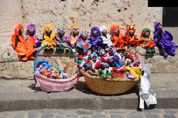 Colorful dolls for sale on a street market in Havana, Cuba, stone wall in the background