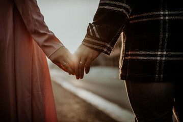 Fototapeta premium Interracial couple, man and woman holding hands, one wearing a gold wedding ring.
