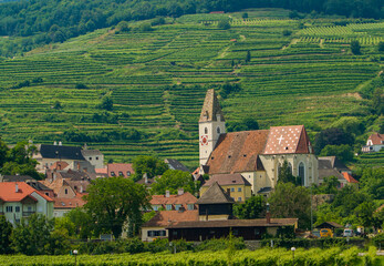 A Christian Church with a clock tower in the Wachau Valley wine region along the Danube River,...