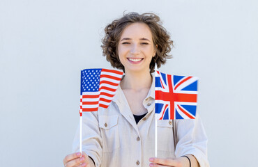 Portrait of a young beautiful woman with two flags USA and UK. Student learns English.