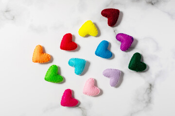 A flat lay of Handmade felt hearts of rainbow colors are on a white background. Pattern.