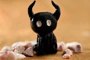 Action figure characterizing a shadow, made of black plasticine, around stones, all placed on recycled paper