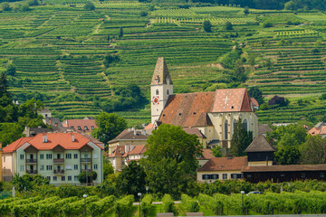 A Christian Church with a clock tower in the Wachau Valley wine region along the Danube River,...