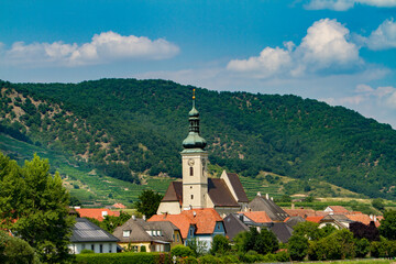 A church with clock tower in the wine region near Durnstein, Austria  A vineyard in the background.