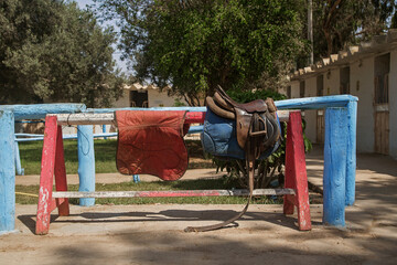horse saddles on a crossbar in the stable