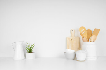 Kitchenware and utensils on a white shelf or countertop with a white wall background and copy...