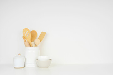 Fototapeta na wymiar Kitchen cooking utensils on a white shelf or counter against a white wall background with copy space