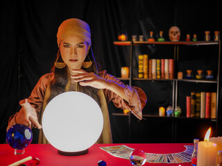 Asian woman fortune teller using divine magical power crystal ball to forecast psychic future luck