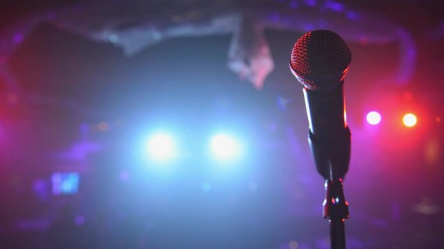 Sweeping close up of stage microphone under colorful spotlights 