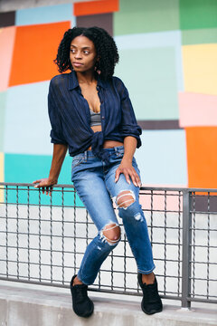 Happy Black Woman Sitting On Fence In Outdoor Portrait 