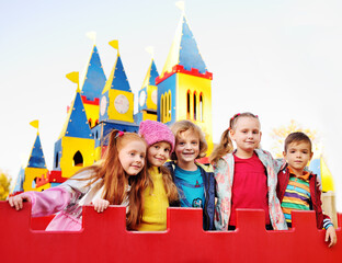 a group of cheerful children play in the amusement Park on the background of a colorful fairy-tale...