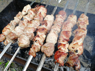pork shish kebab on skewers is fried on coals in the grill. Top view, flat lay, picnic, unhealthy food