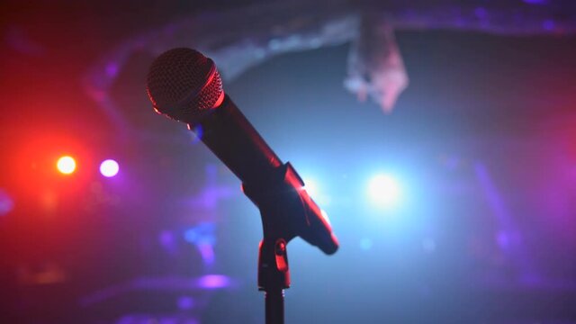 Sweeping close up of stage microphone under colorful spotlights 
