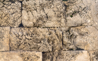 An old wall made of rectangular natural rough stones.