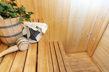 Obraz na płótnie Canvas Interior details Finnish sauna steam room with traditional sauna accessories basin birch broom scoop felt hat towel. Traditional old Russian bathhouse SPA Concept. Relax country village bath concept.