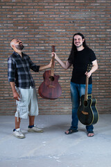 Happy adult males holding guitars having fun in a performance.