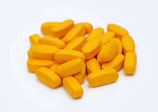 Big orange pills on a white background. Oval tablets of calcium and magnesium. Dietary supplements in capsule form.