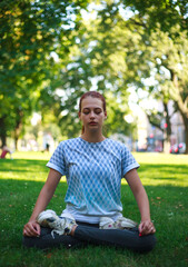 Concentrated young girl doing yoga exercises in summer green city park