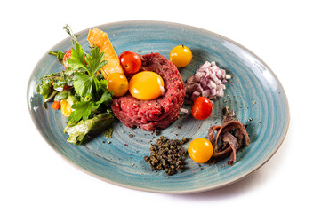 Traditional German food. Mett, Hackepeter on a plate with raw egg, tomatoes, parsley and chopped onions