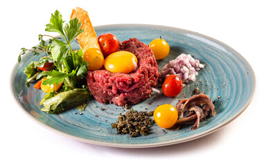 Traditional German food. Mett, Hackepeter on a plate with raw egg, tomatoes, parsley and chopped onions