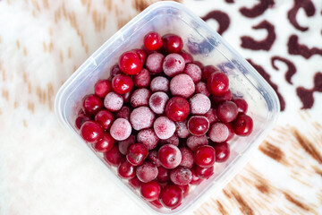frozen cherries with a bloom of frost on the fruits. Container with red berries.