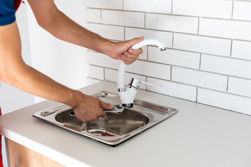 Plumber putting a silicone sealant to installing a kitchen sink