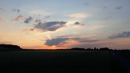 Ende eines Tages - Sonnenuntergang mit Wolken bei schönem Wetter und Hitze im Sommer