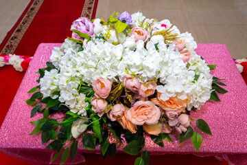 A bunch of colorful flowers arranged in a bouquet on a pink table.