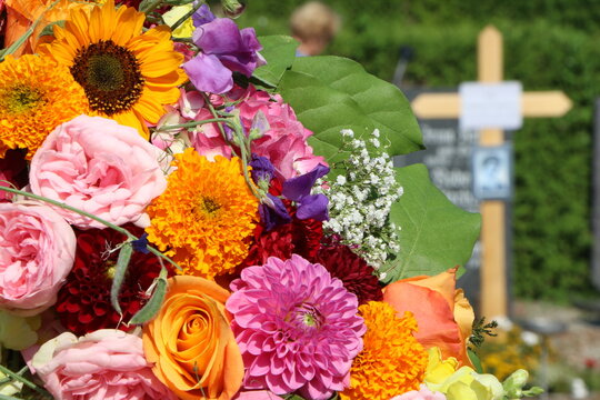 Bunter Blumenkranz an einem Friedhof nach einer Beisetzung, Bestattung, Grabpflege, christlicher Friedhof 
