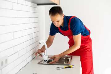 partial view of repairman in working overall fixing sink in kitchen