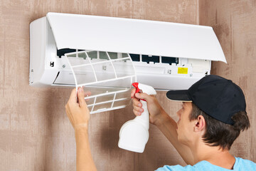 caucasian male technician service worker cleaning air conditioner indoors. diy maintenance concept