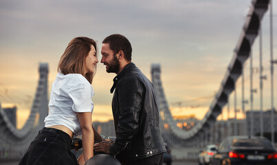Love and romantic concept. Beautiful couple on motorcycle stands opposite each other in the middle of the road on the bridge, on double solid
