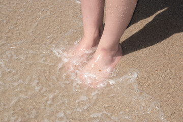 Waves rolling over feet on the beach