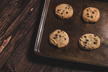 Fresh baked chocolate chip cookies still in the baking pan on a wooden table top.