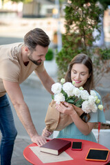 Pretty female holding bouquet of white flowers presented by bearded female