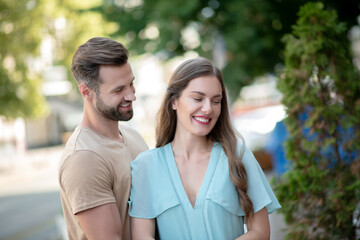 Bearded male hugging tenderly smiling female in blue dress