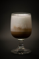 Tasty Italian coffee in a big glass. Is a typical mix of coffee and milk, is a n Italian cappuccino in a large fancy glass. All with a black background
