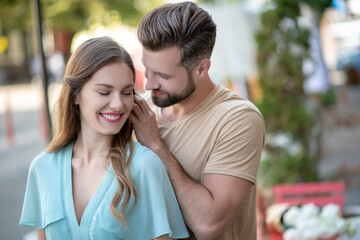 Bearded male standing beside female in blue dress, stroking her hair