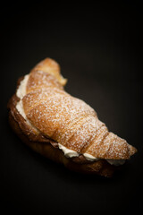 freshly plain croissant for breakfast with handmade cream and sugar on a black background, italian breakfast