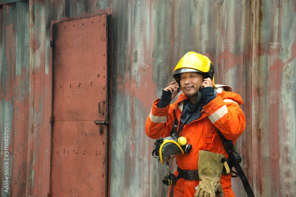 Wall mural the portrait of asian firefighters are wearing orange fire protection uniform mask and helmet front 