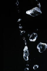 Splash and water droplets with ice falling, freezing in motionSplash and drops of water with ice falling, freezing in motion, on a black background
