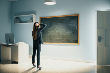 Businesswoman looking on blank blackboard.