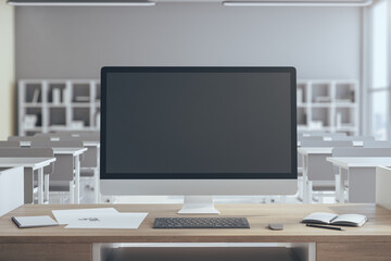 Black computer screen on table in luxury classroom interior.